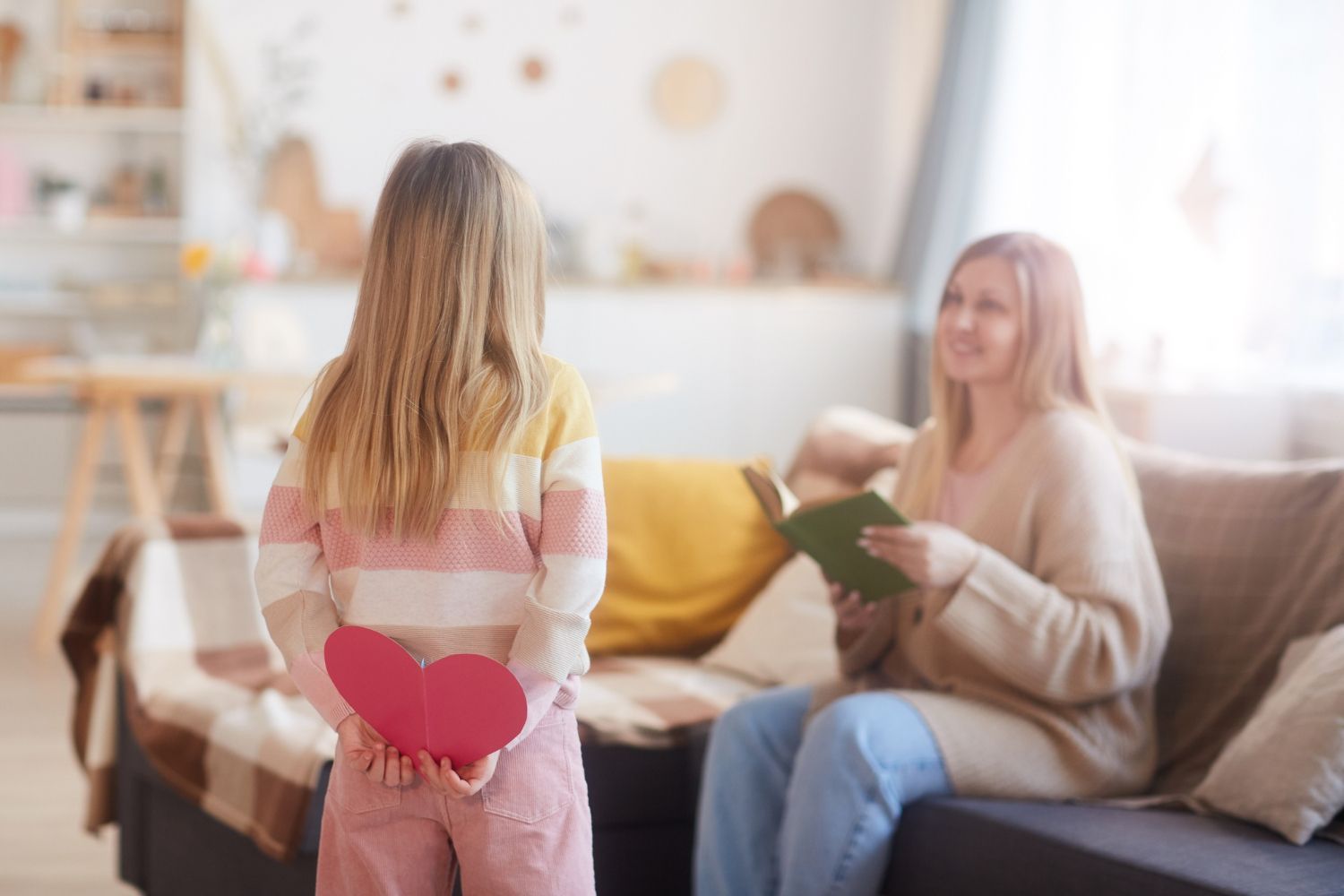 Child holding a paper heart with a parent sitting nearby