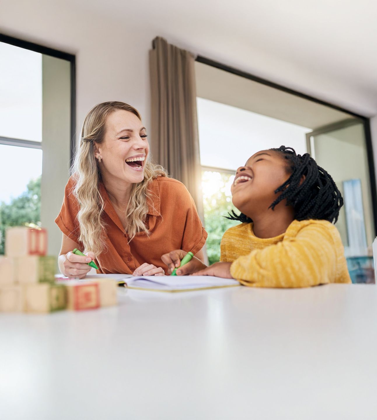 Therapist and child laughing together at a table